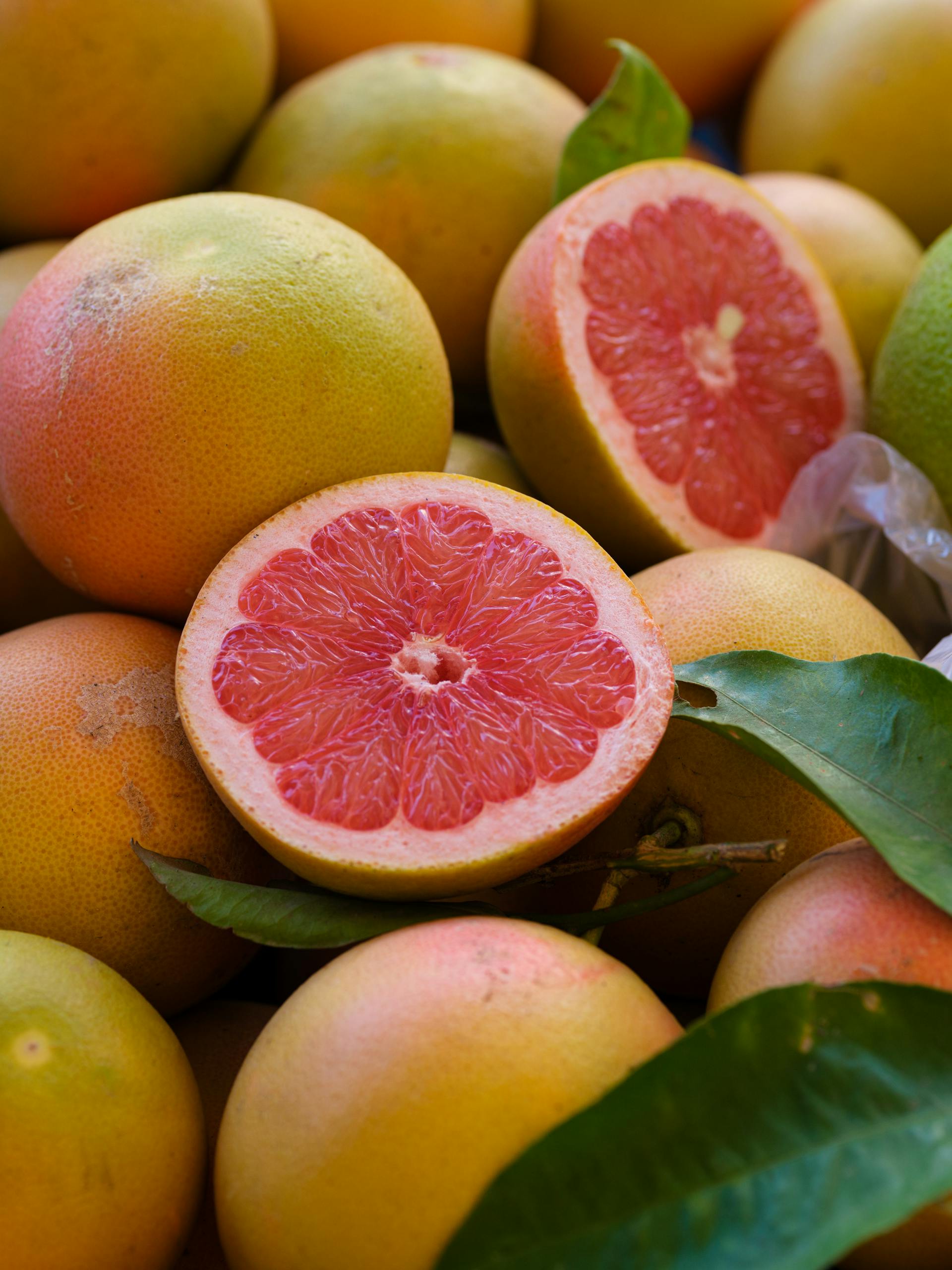 Close-up of fresh, ripe grapefruits with a sliced half showcasing vibrant pulp.
