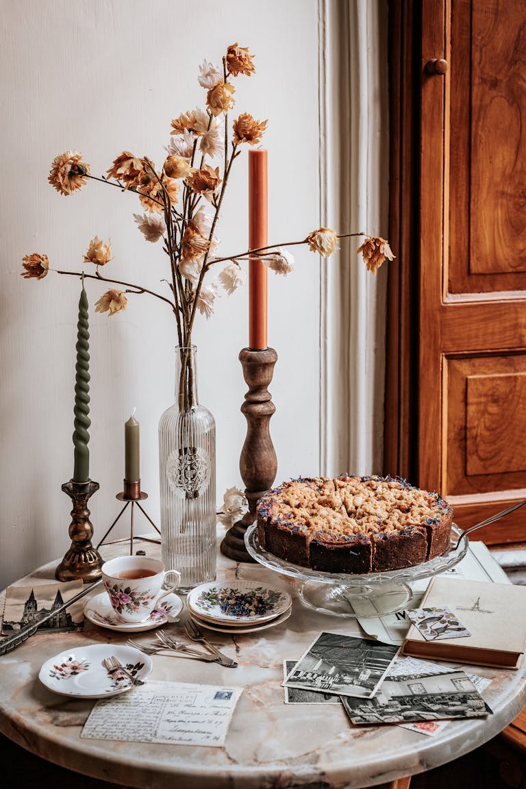 A cozy autumn still life with cake, candles, and postcards on a vintage table.
